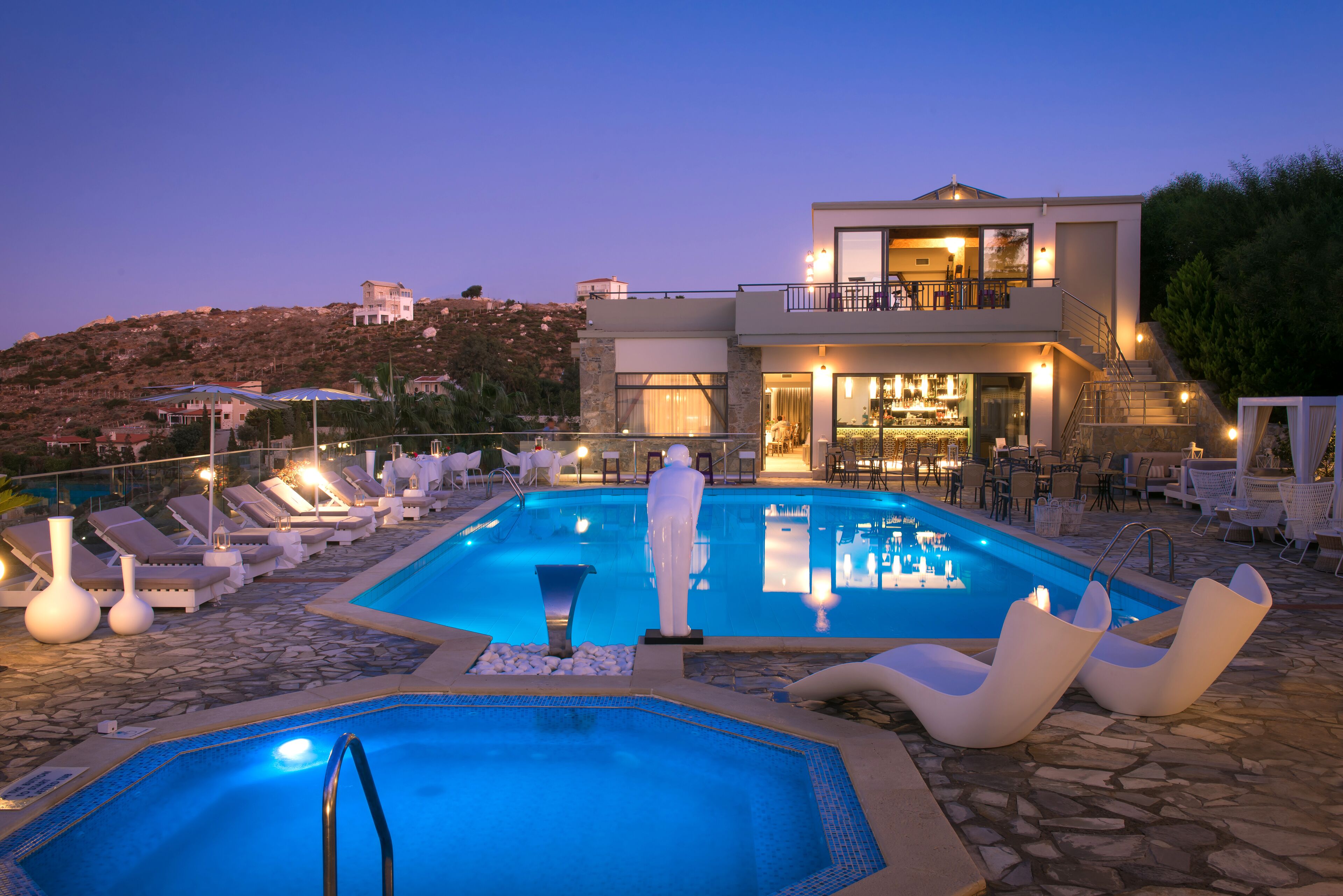 Ein moderner Poolbereich mit Liegestühlen, einem Whirlpool und einer Bar.