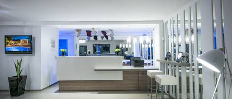 A modern reception area with a counter, seating, and a TV.