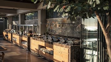 A buffet setup with a stone wall, wooden cabinets, and a glass enclosure.