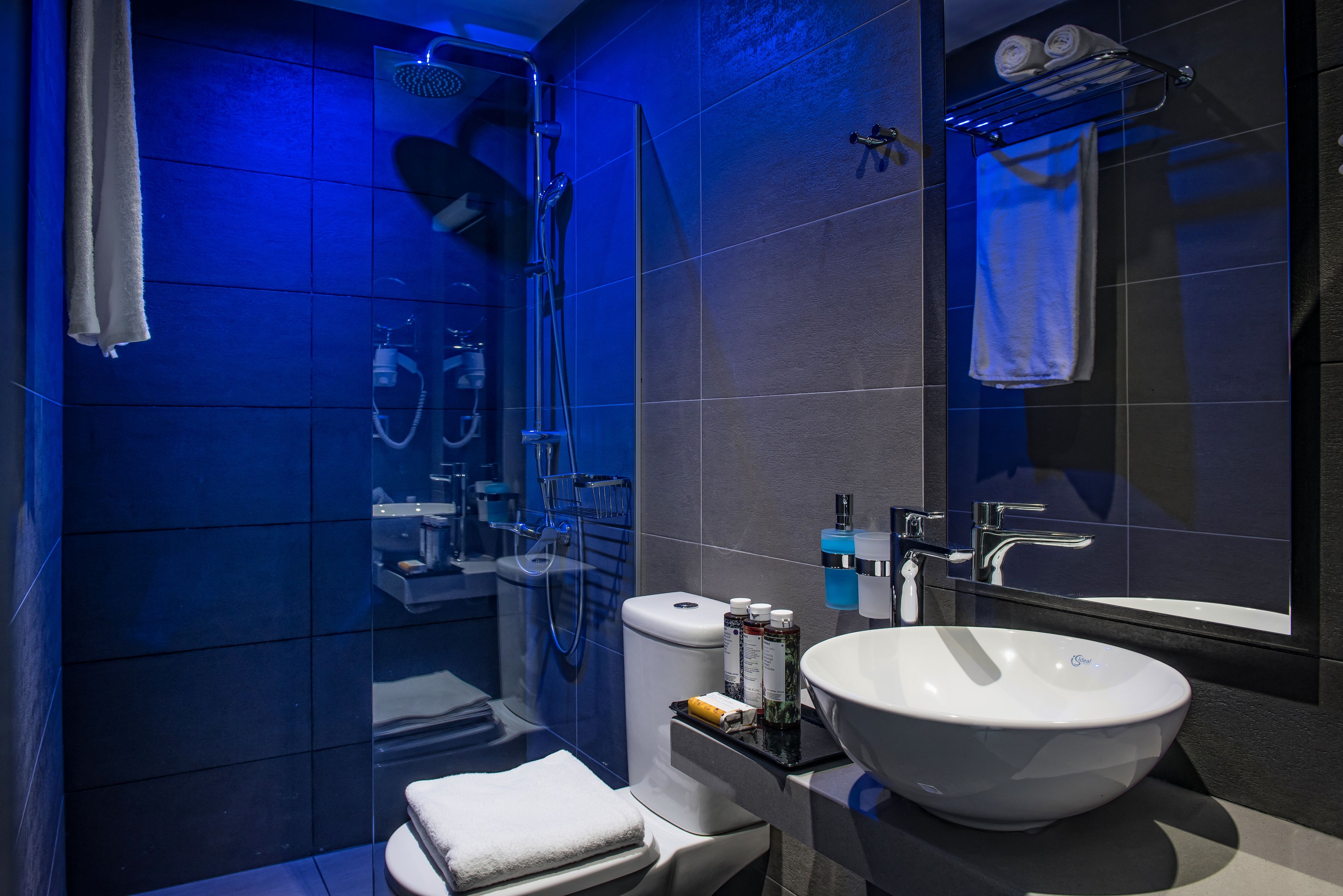 Une salle de bain moderne avec une douche à parois de verre, un lavabo blanc et un grand miroir.