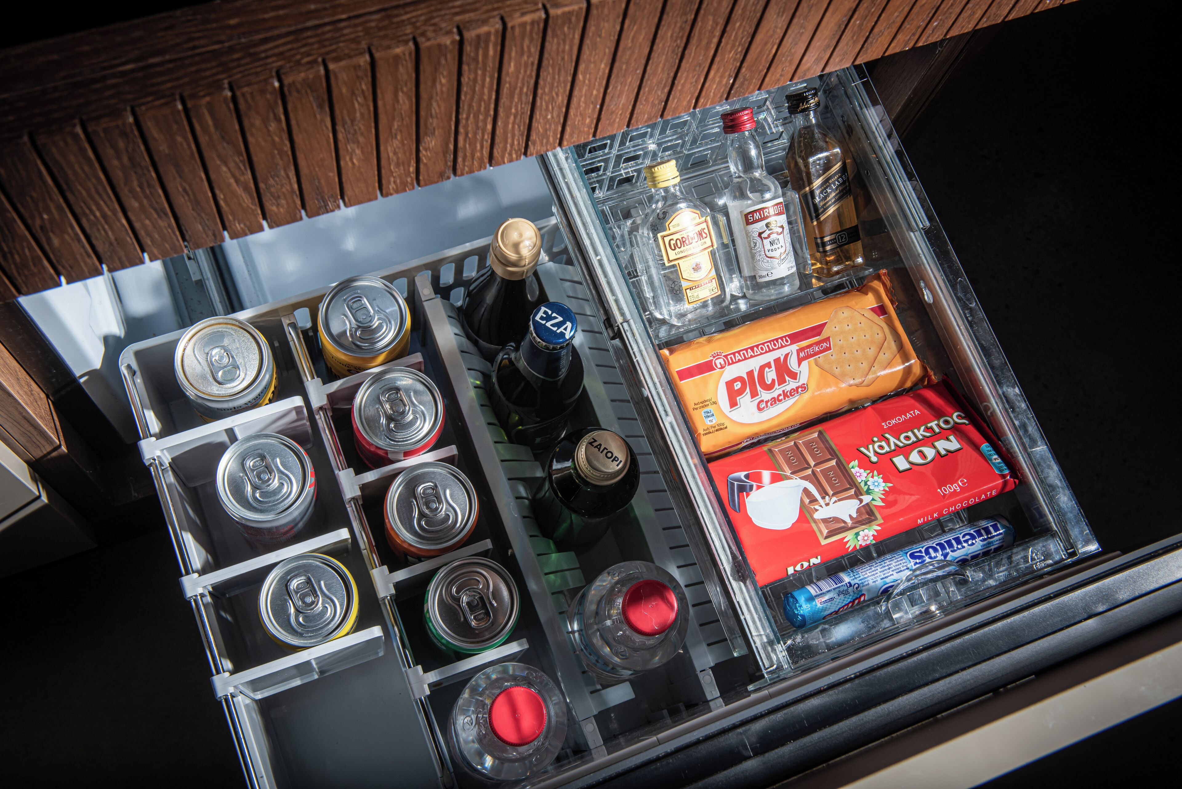 Eine Minibar mit verschiedenen Getränken, Snacks und einer Wasserflasche.