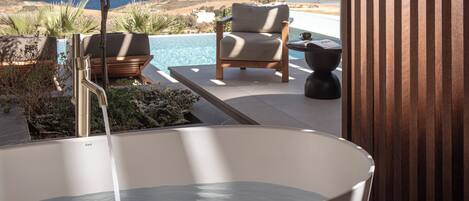 A hot tub with a towel, two chairs, and a view of the ocean.