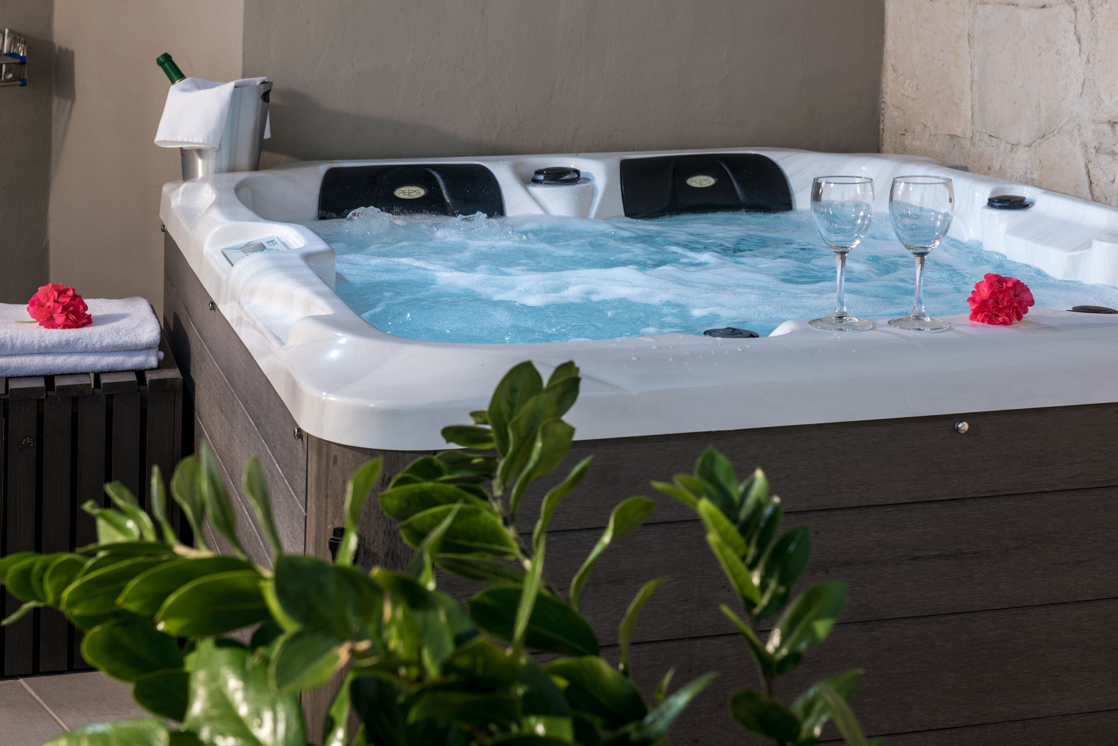 Ein Whirlpool mit zwei Gläsern Wasser, einem Handtuch und einer Blume auf einer Ablagefläche.