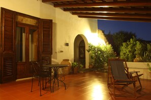 An outdoor patio with a table and chairs, a wooden door, and potted plants. - Albergo Villa Diana (Lipari)
