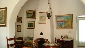 Un accogliente soggiorno con soffitto a volta alto, arredi in legno e diverse opere d'arte incorniciate alle pareti.