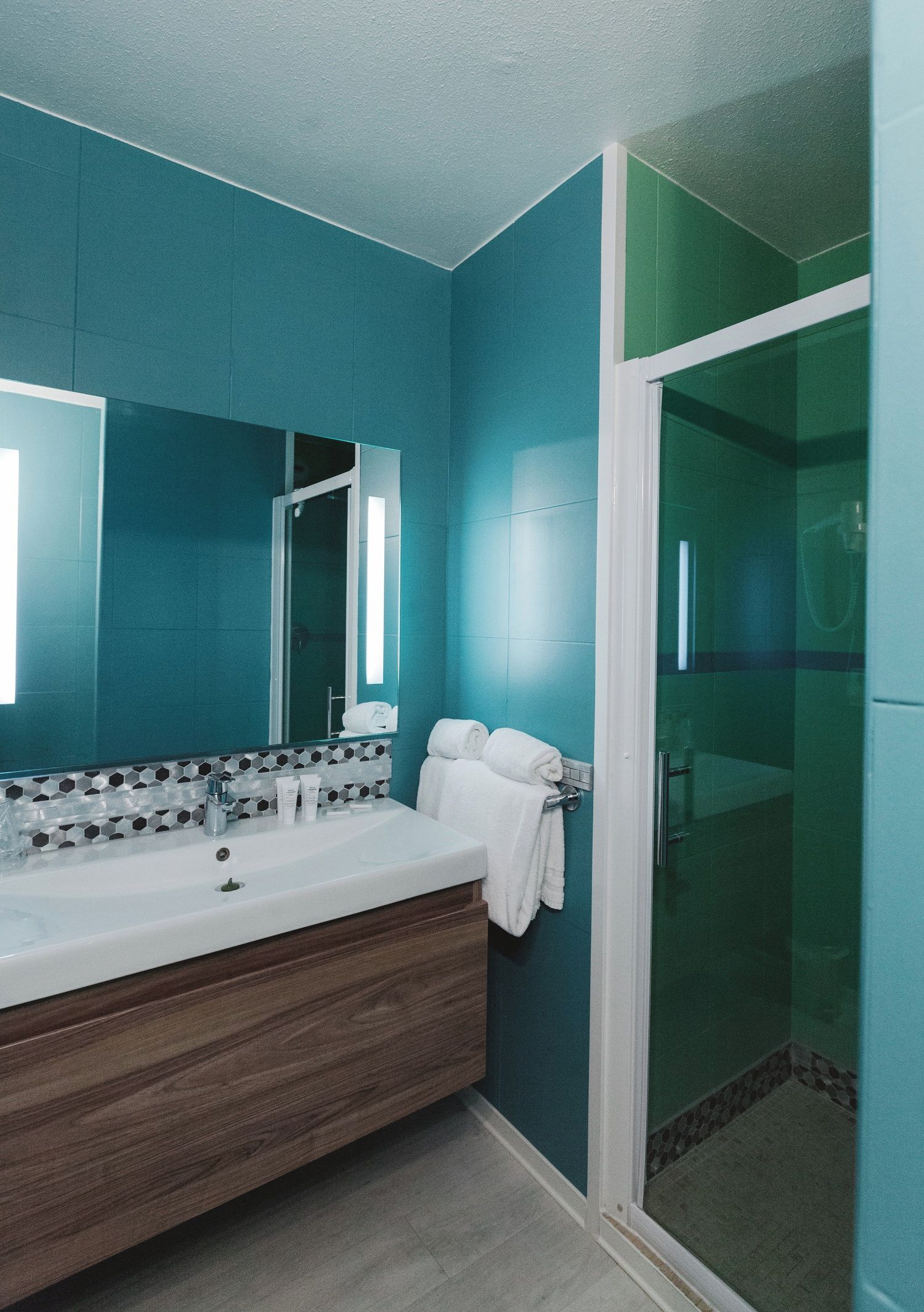 A bathroom with a large mirror, a sink, and a shower area.