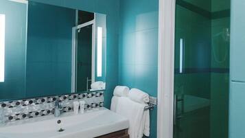 A bathroom with a large mirror, a sink, and a shower area.
