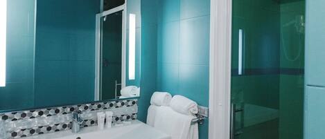 A bathroom with a large mirror, a sink, and a shower area.