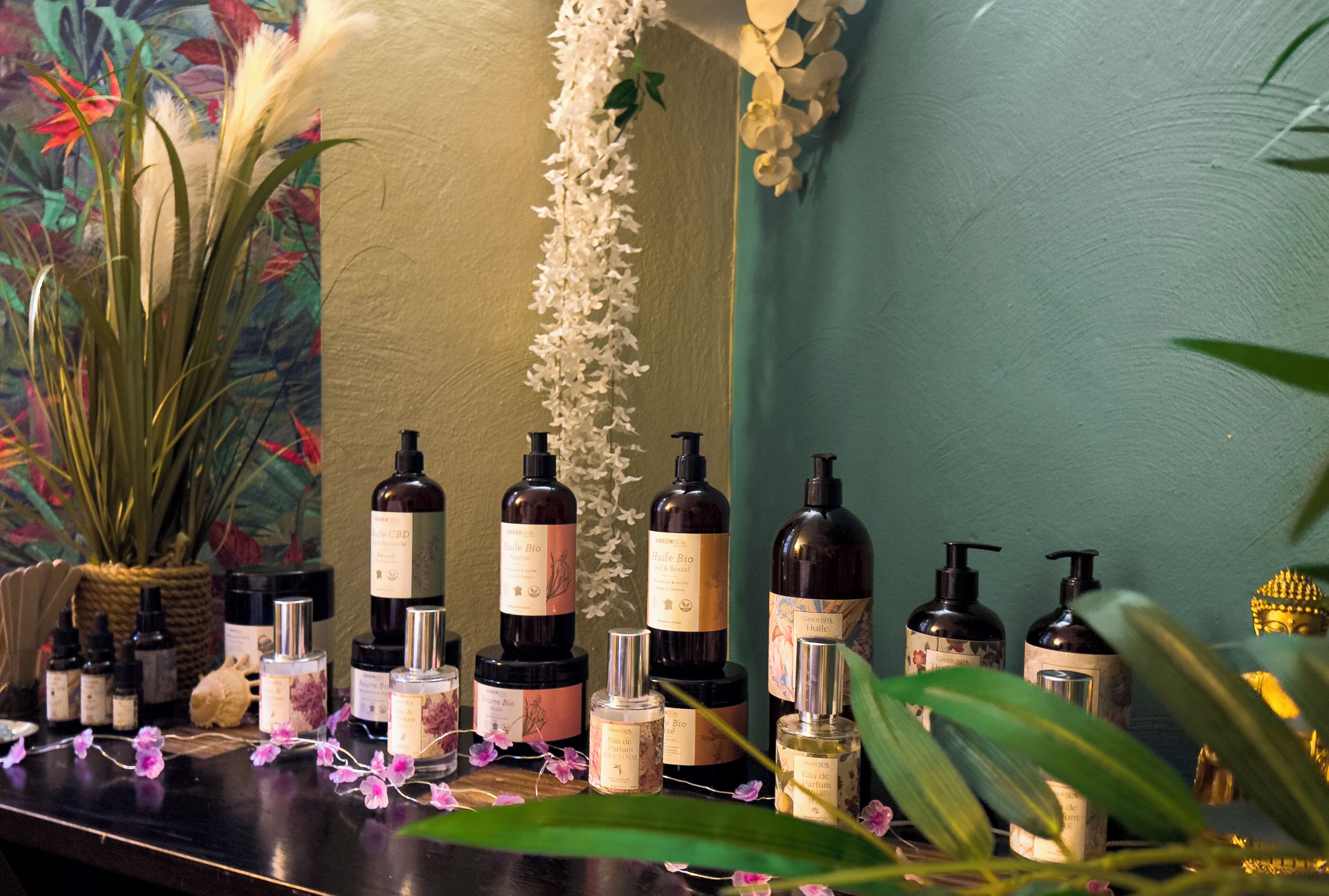 A display of various skincare products on a counter with decorative plants and flowers.