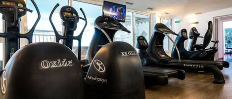 A gym with various exercise equipment including treadmills, ellipticals, and weight machines.