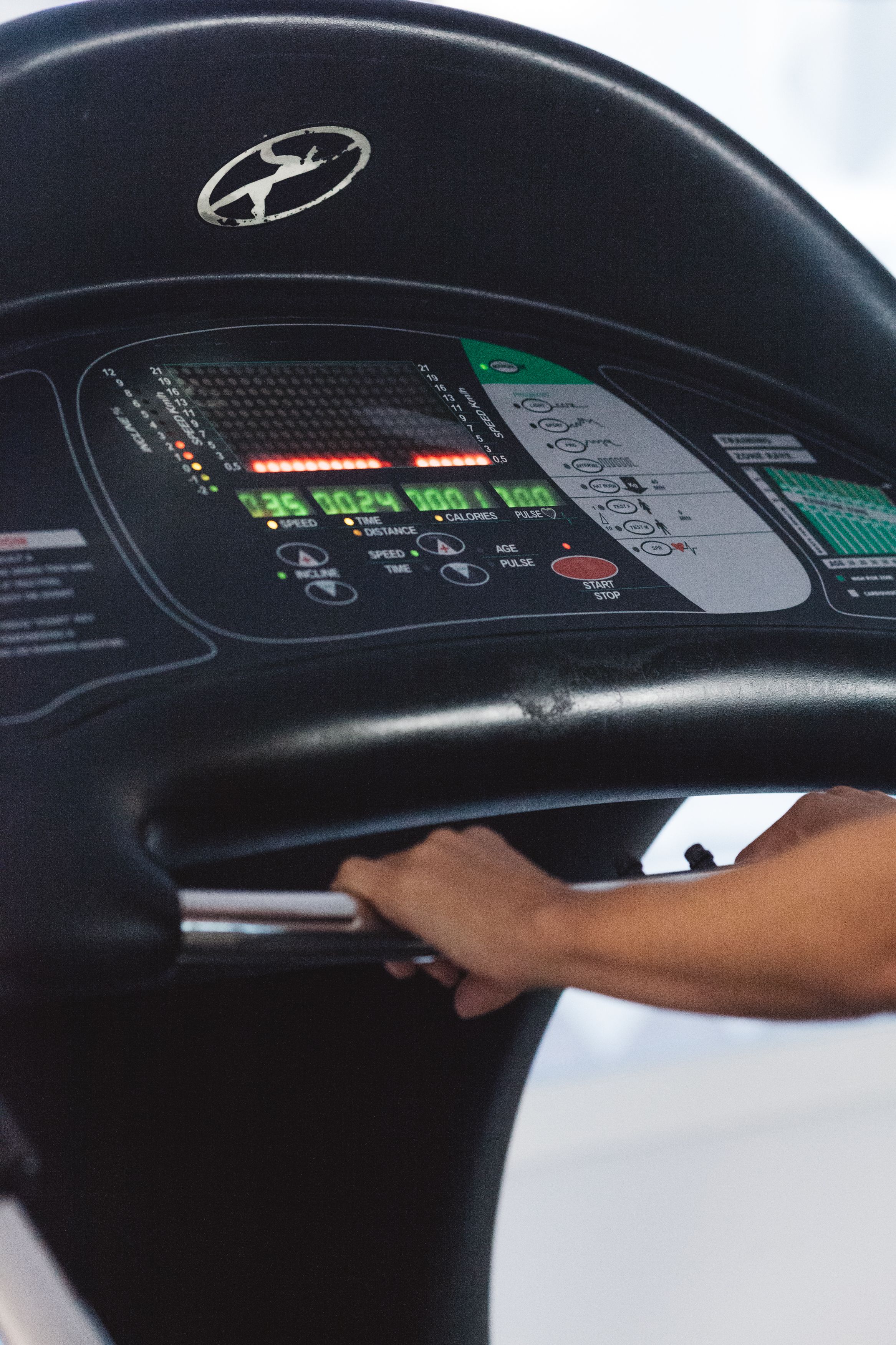 Panel de control de cinta de correr con pantalla digital y botones para velocidad, tiempo y otras configuraciones.
