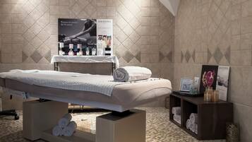 A spa room with a massage table, a poster of Sothys products, and a tiled floor.