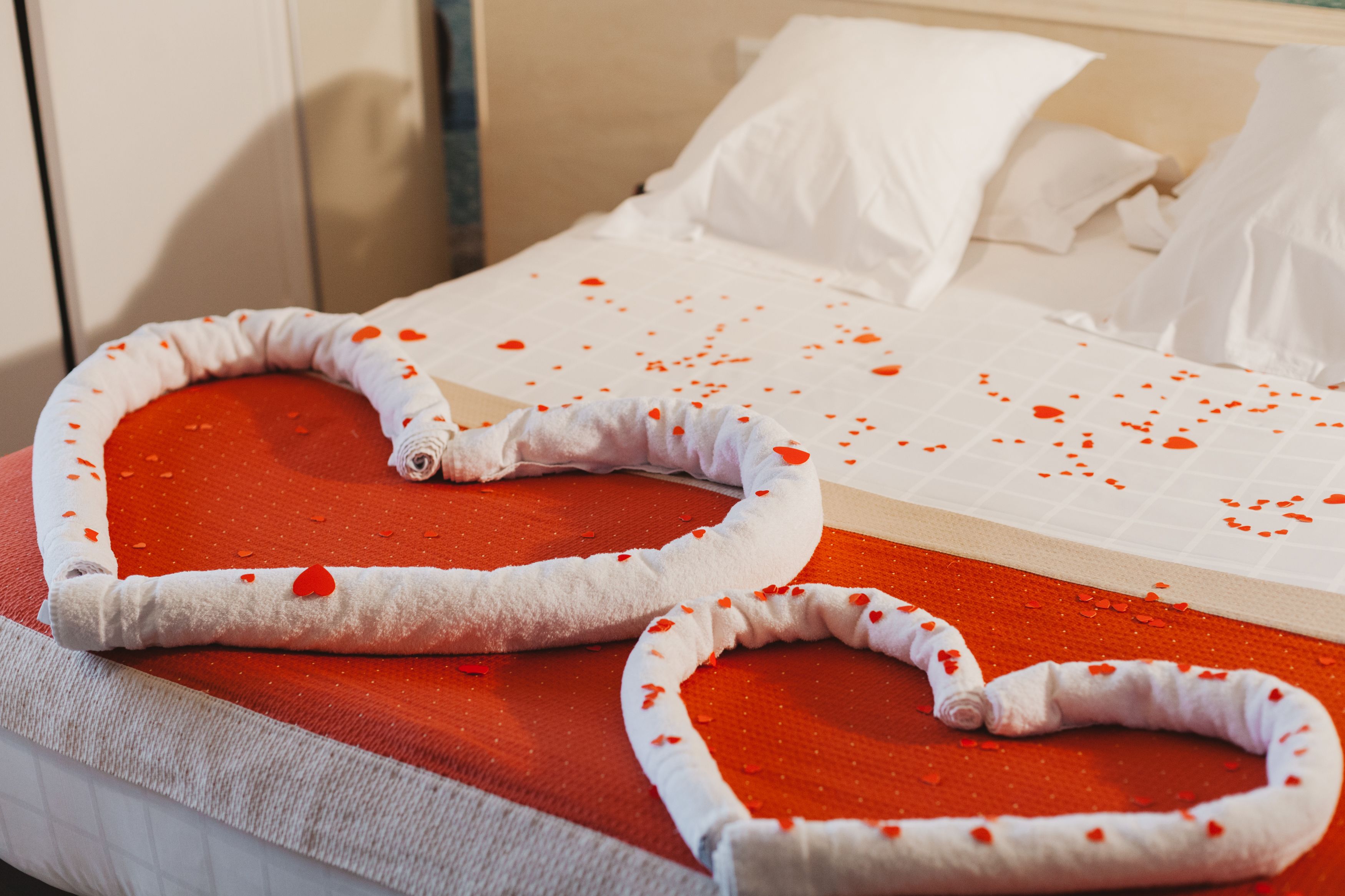 A bed with a red heart-shaped bedspread and white pillows.