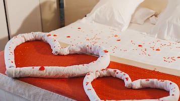 A bed with a red heart-shaped bedspread and white pillows.