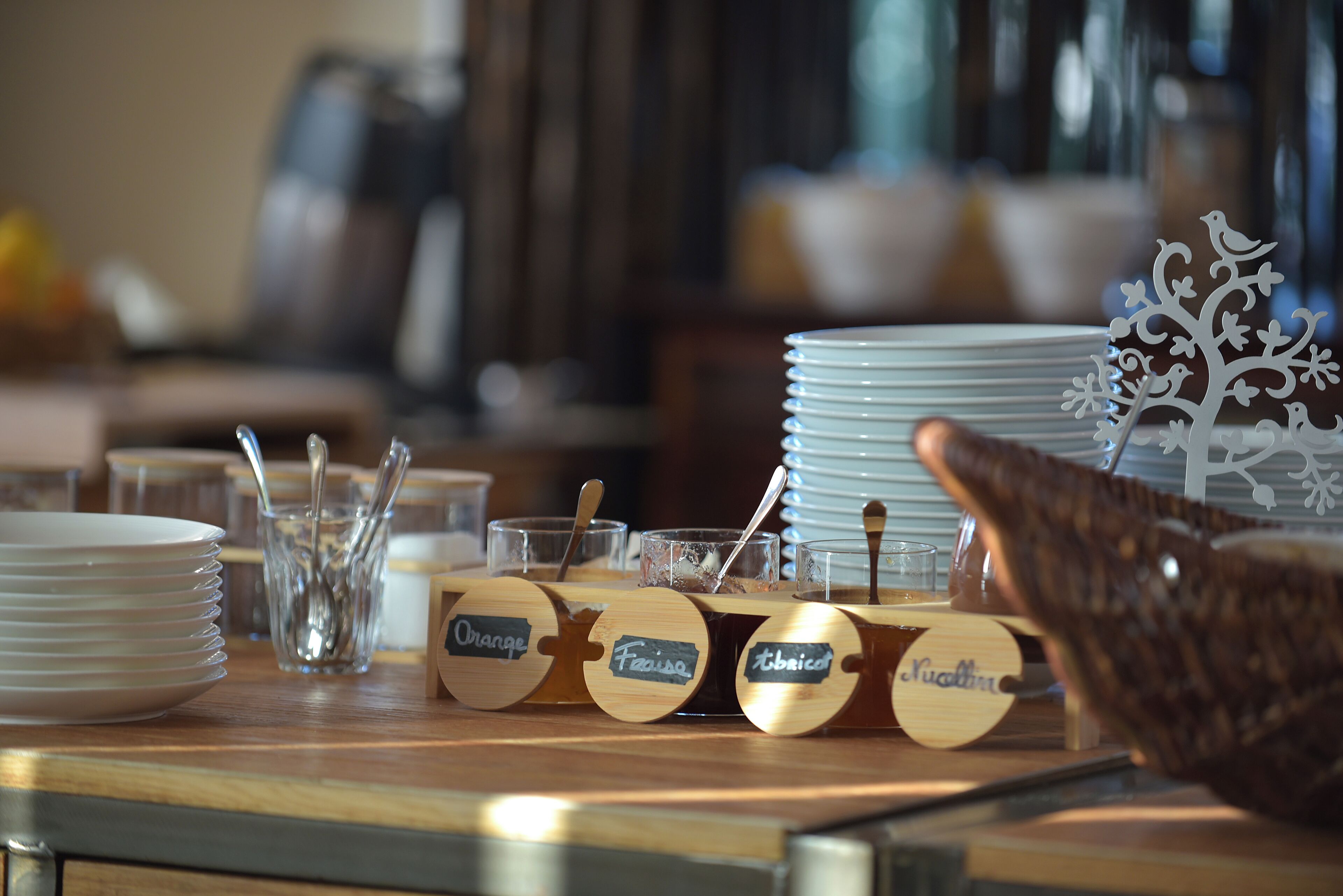 A table with labeled wooden containers, plates, and glasses, likely for serving food or drinks.