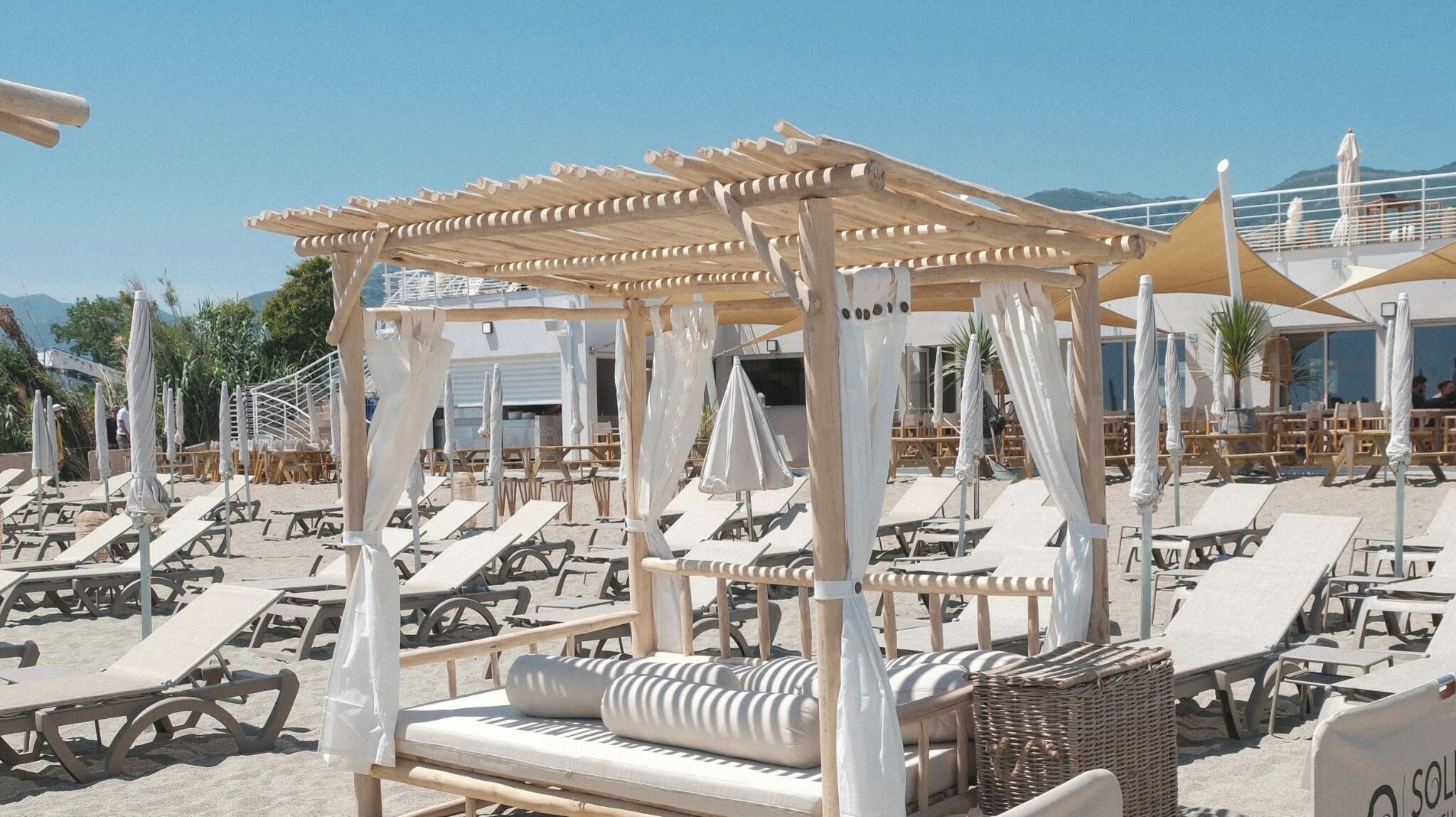 Un área de descanso junto a la playa con tumbonas y una estructura de madera con techo.