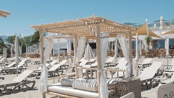 Un área de descanso junto a la playa con tumbonas y una estructura de madera con techo.