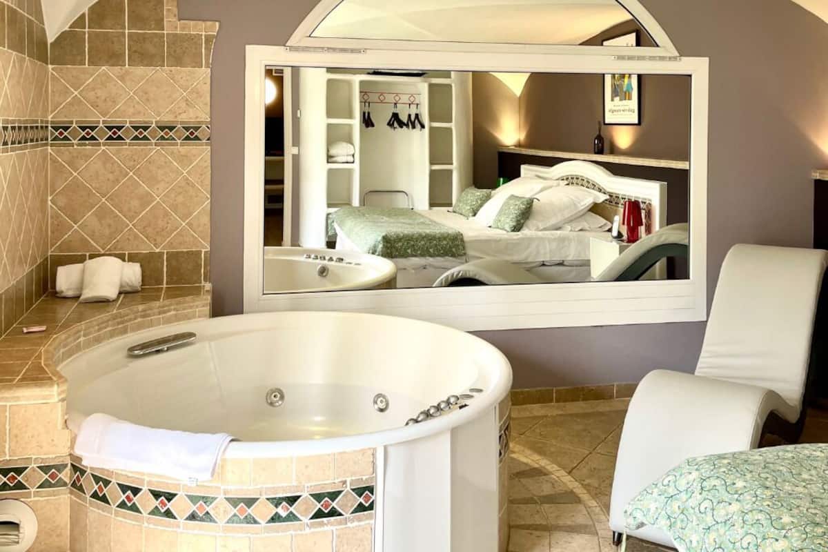 A modern bathroom with a large bathtub, a mirror, and a shower area.