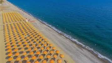 En privat strand, liggestole, parasoller, snorkling
