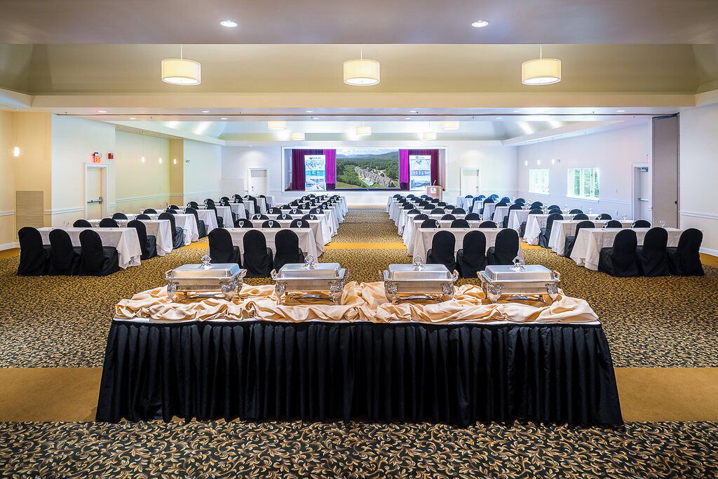 A conference room with rows of tables, chairs, and a buffet setup.