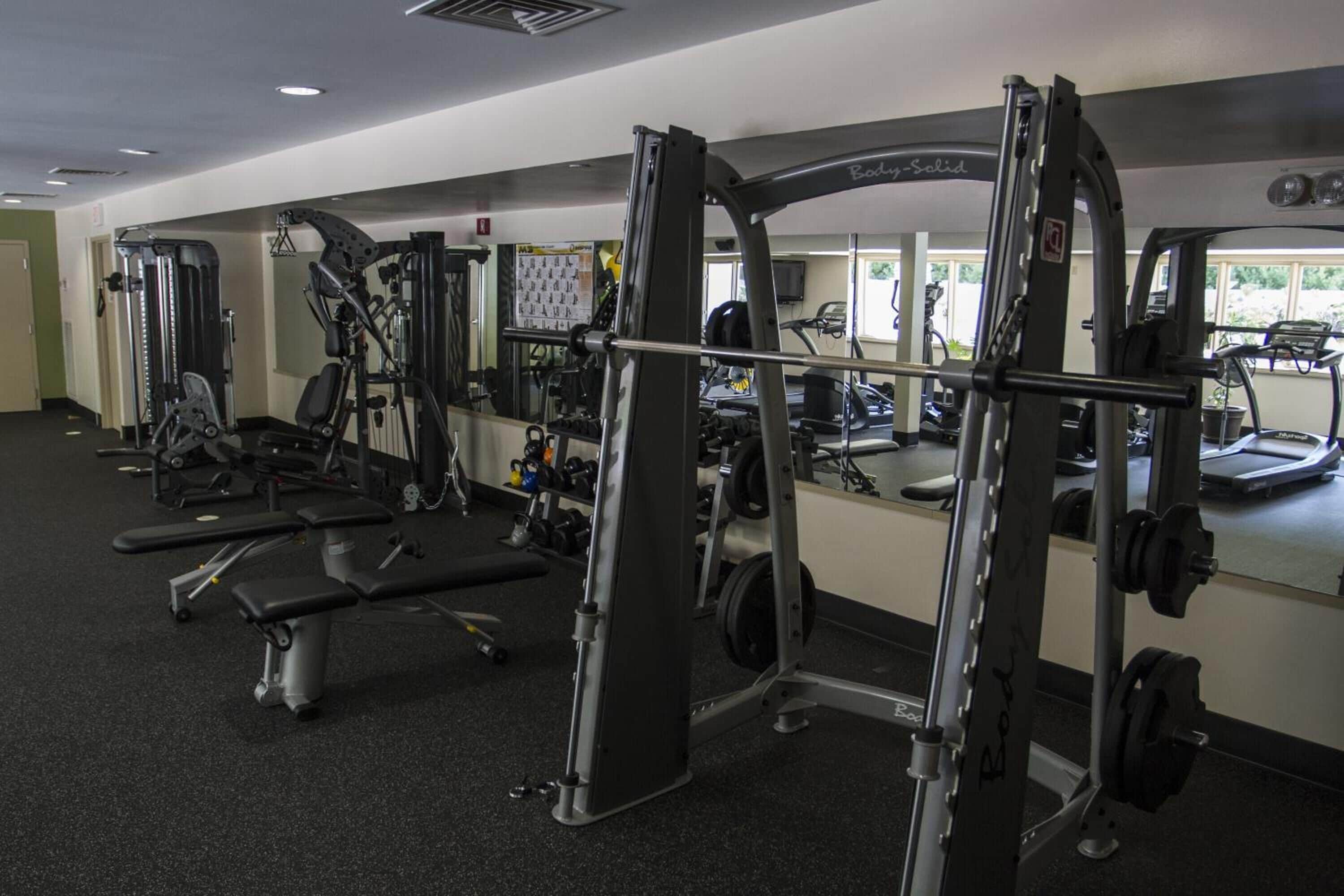 A gym with various exercise equipment, including weight machines and free weights.