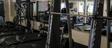 A gym with various exercise equipment, including a squat rack, benches, and weight machines.