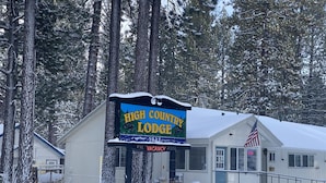 Une enseigne pour le High Country Lodge, avec un paysage enneigé et de grands arbres en arrière-plan.
