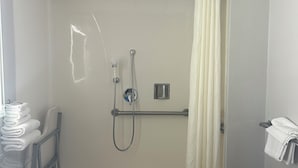 Une douche à l’italienne avec une porte en verre, un porte-serviettes et un pommeau de douche.