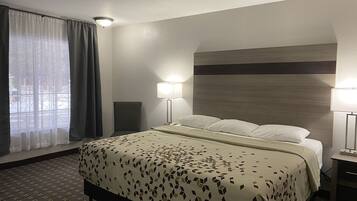 Ein Hotelzimmer mit einem Bett, zwei Nachttischen mit Lampen, einem Fenster mit Vorhängen und einer Kopfteil.