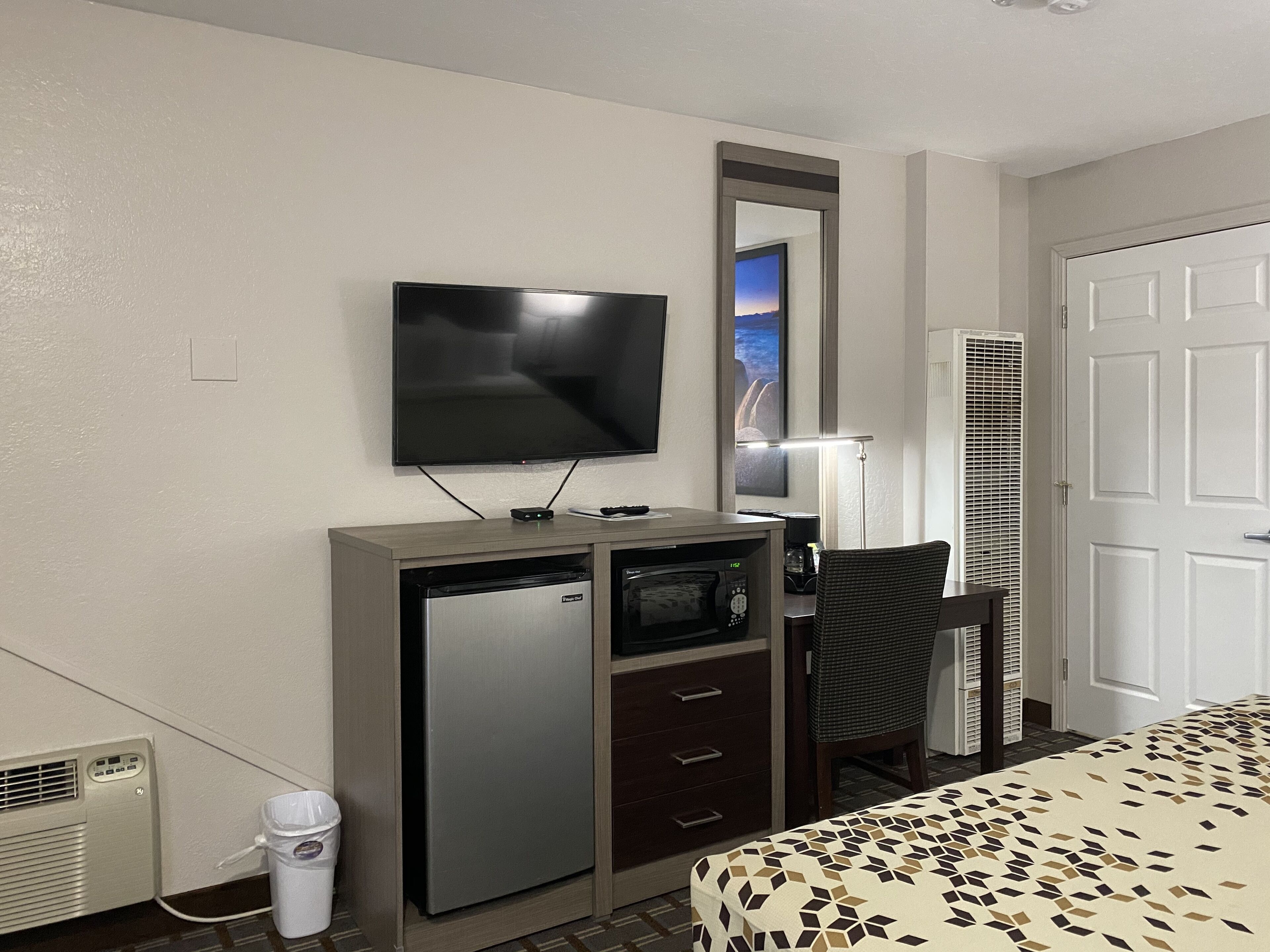 Une chambre d’hôtel comprenant un lit, un bureau avec un micro-ondes, une télévision et une chaise.