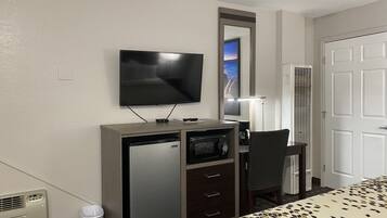 Une chambre d’hôtel comprenant un lit, un bureau avec un micro-ondes, une télévision et une chaise.