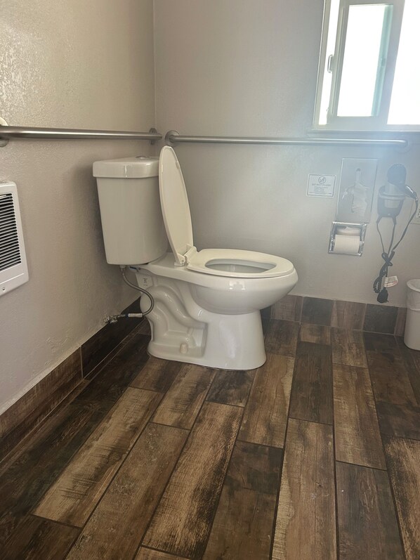 A bathroom with a white toilet, a hand dryer, and a paper towel dispenser.