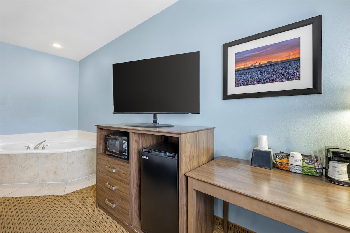 A modern bathroom with a bathtub, a flat-screen TV, a microwave, and a coffee maker.