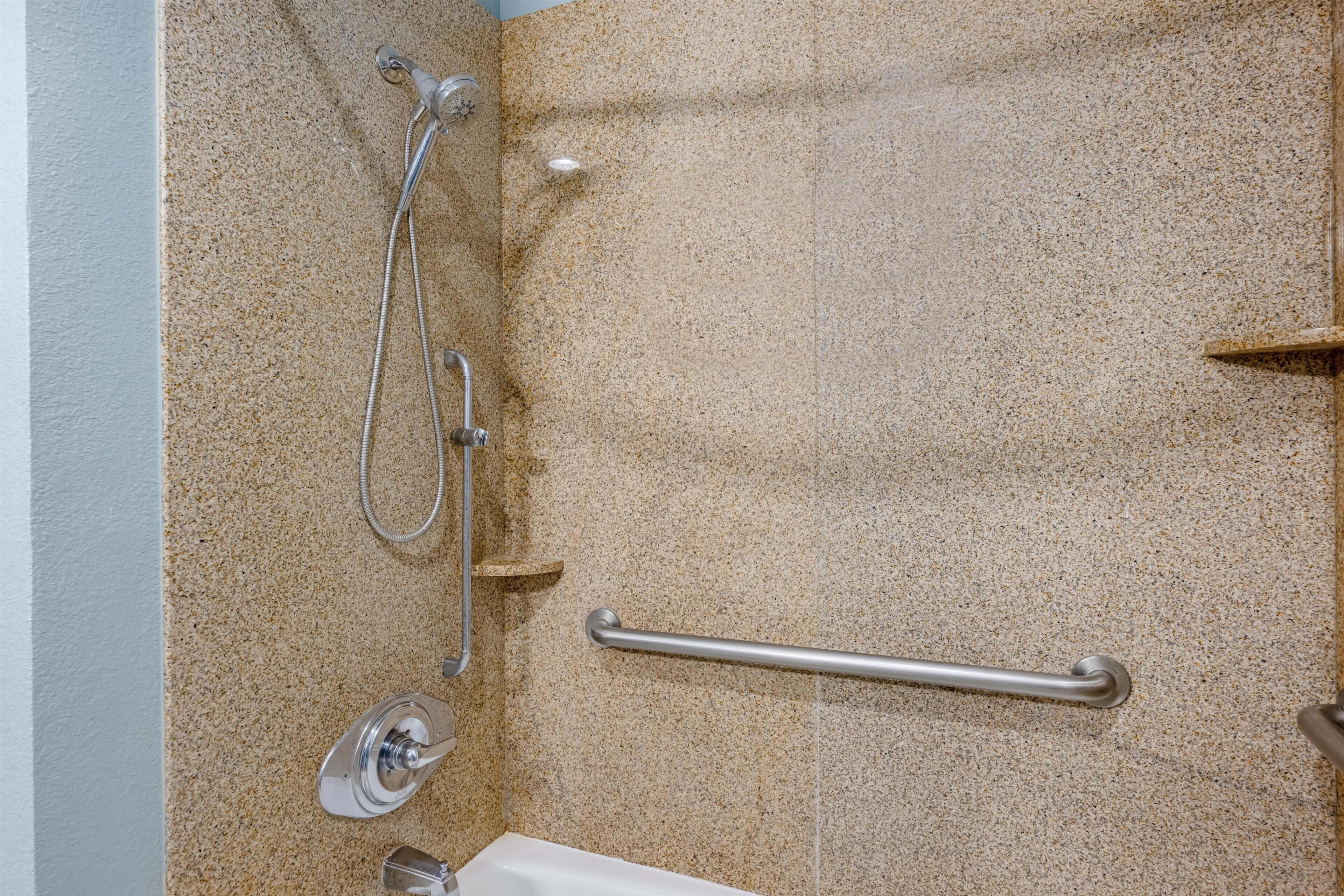 A bathroom with a shower, grab bar, and a bathtub.
