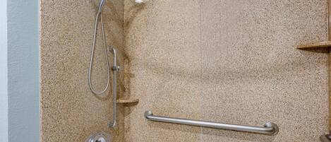 A bathroom with a shower, grab bar, and a bathtub.