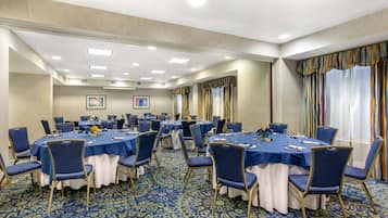 Un salón de conferencias con mesas redondas, manteles azules y sillas a juego.