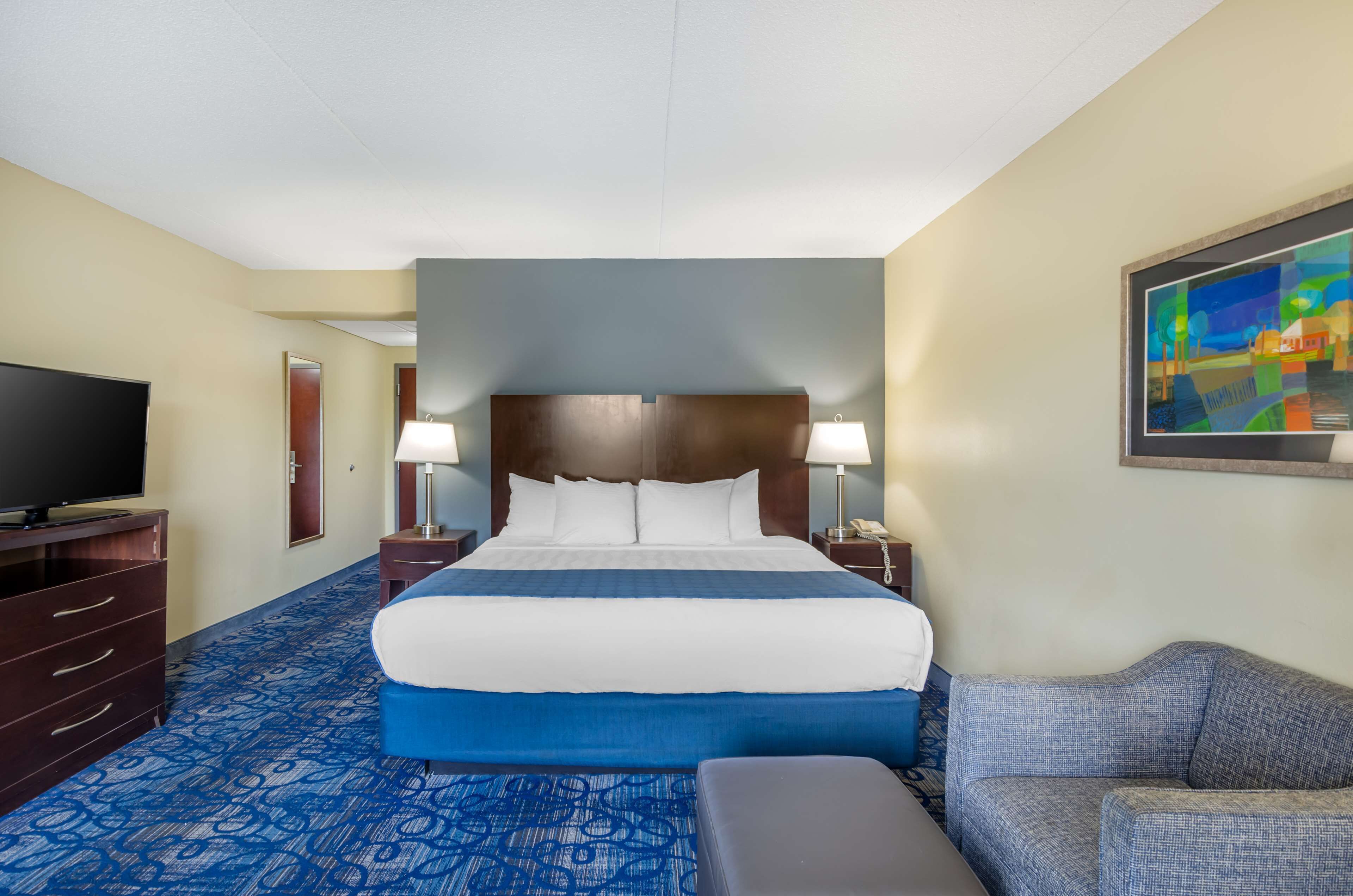 Een hotelkamer met een groot bed, een televisie, een bureau en een bank.