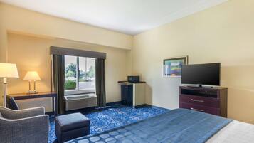 A hotel room with a bed, a desk, a chair, a television, and a window with curtains.