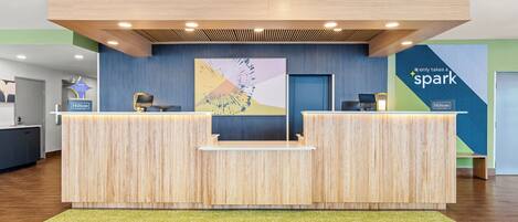 Un comptoir d’accueil au design moderne, doté d’un écran numérique et arborant le logo de Hilton.