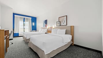 A hotel room with two beds, a desk, a chair, and a large window with curtains.
