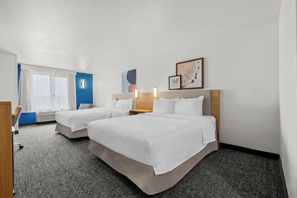 A hotel room with two beds, a desk, a chair, a window with curtains, and wall art. - Spark by Hilton Pelham Birmingham I 65 (Pelham)