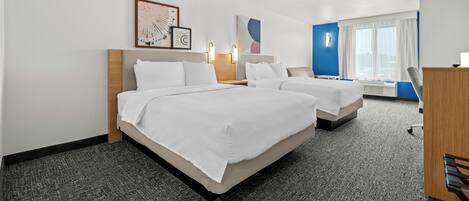 Een hotelkamer met twee bedden, een bureau en een raam met gordijnen.