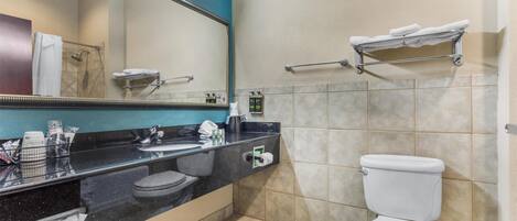 A bathroom with a black countertop, white sink, and a white toilet.