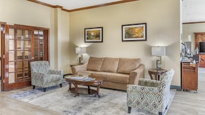 A living room with a beige sofa, patterned armchairs, a coffee table, and a wooden cabinet. - Best Western Mineola Inn (Mineola)