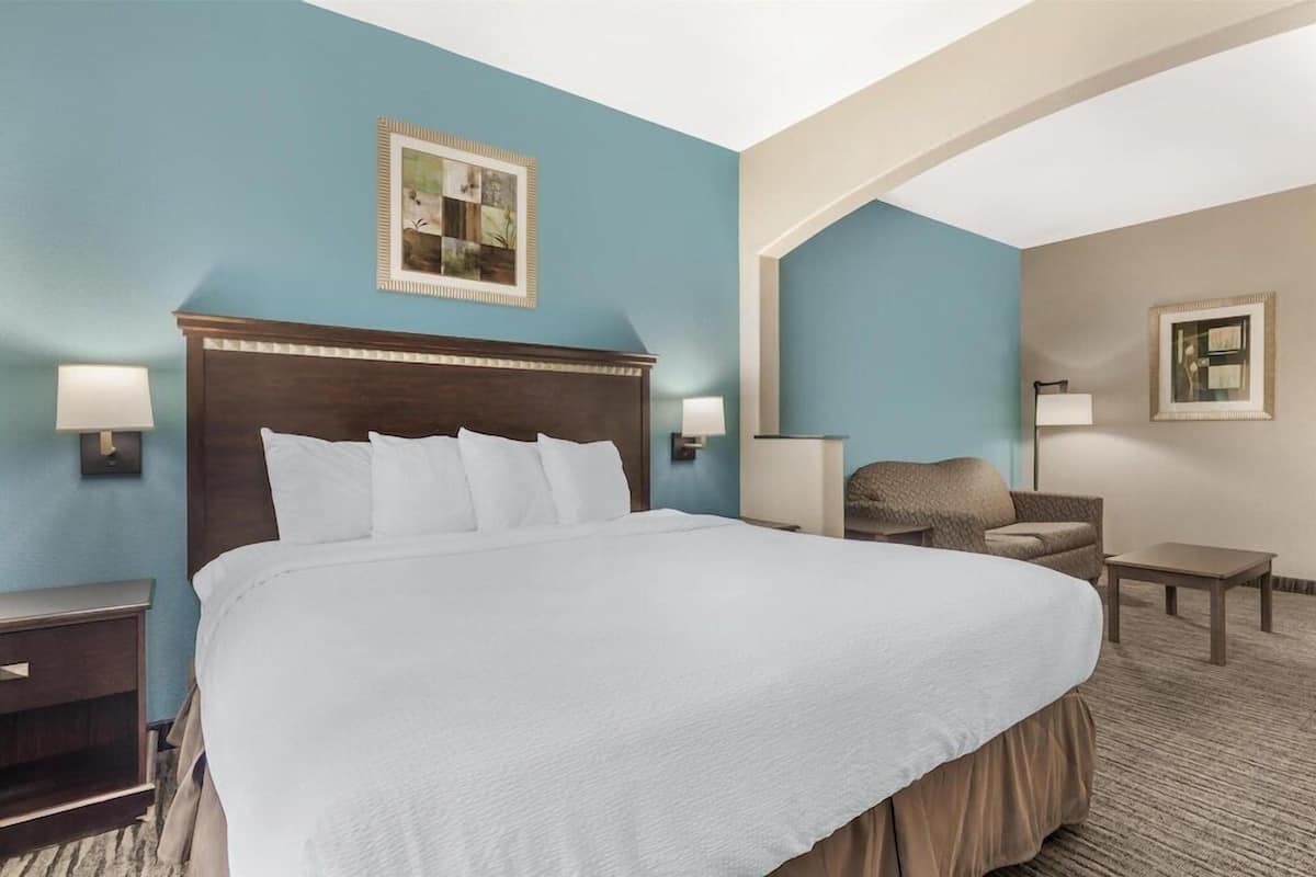 A hotel room with a large bed, two bedside tables, a chair, and a small table.