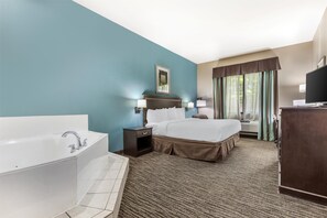 A hotel room with a large bed, a separate bathroom with a bathtub, a desk with a television, and a window with curtains. - Best Western Mineola Inn (Mineola)