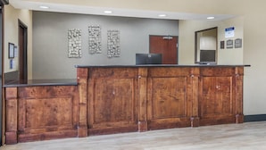 A reception desk with a wooden finish, a flat-screen TV, and a wall-mounted information board. - Best Western Mineola Inn (Mineola)
