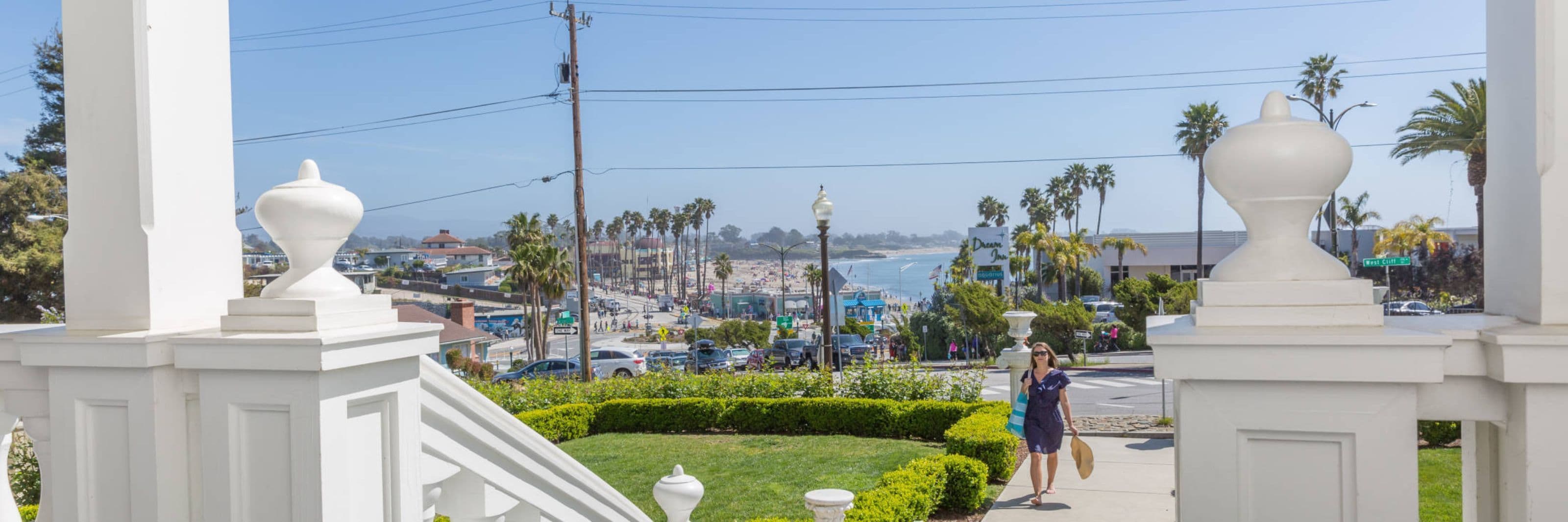 Un paysage urbain côtier avec des palmiers, une plage et une promenade piétonne.