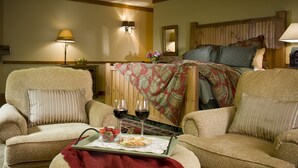 A cozy room with a bed, two armchairs, a small table with snacks and wine glasses, and a lamp. - Lake Opechee Inn and Spa (Laconia)