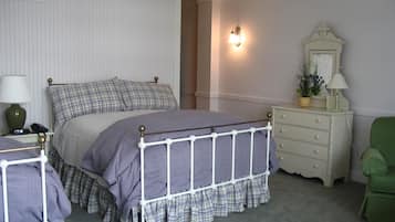 Ein Schlafzimmer mit Bett, Kommode, Stuhl und Nachttisch mit Lampe.